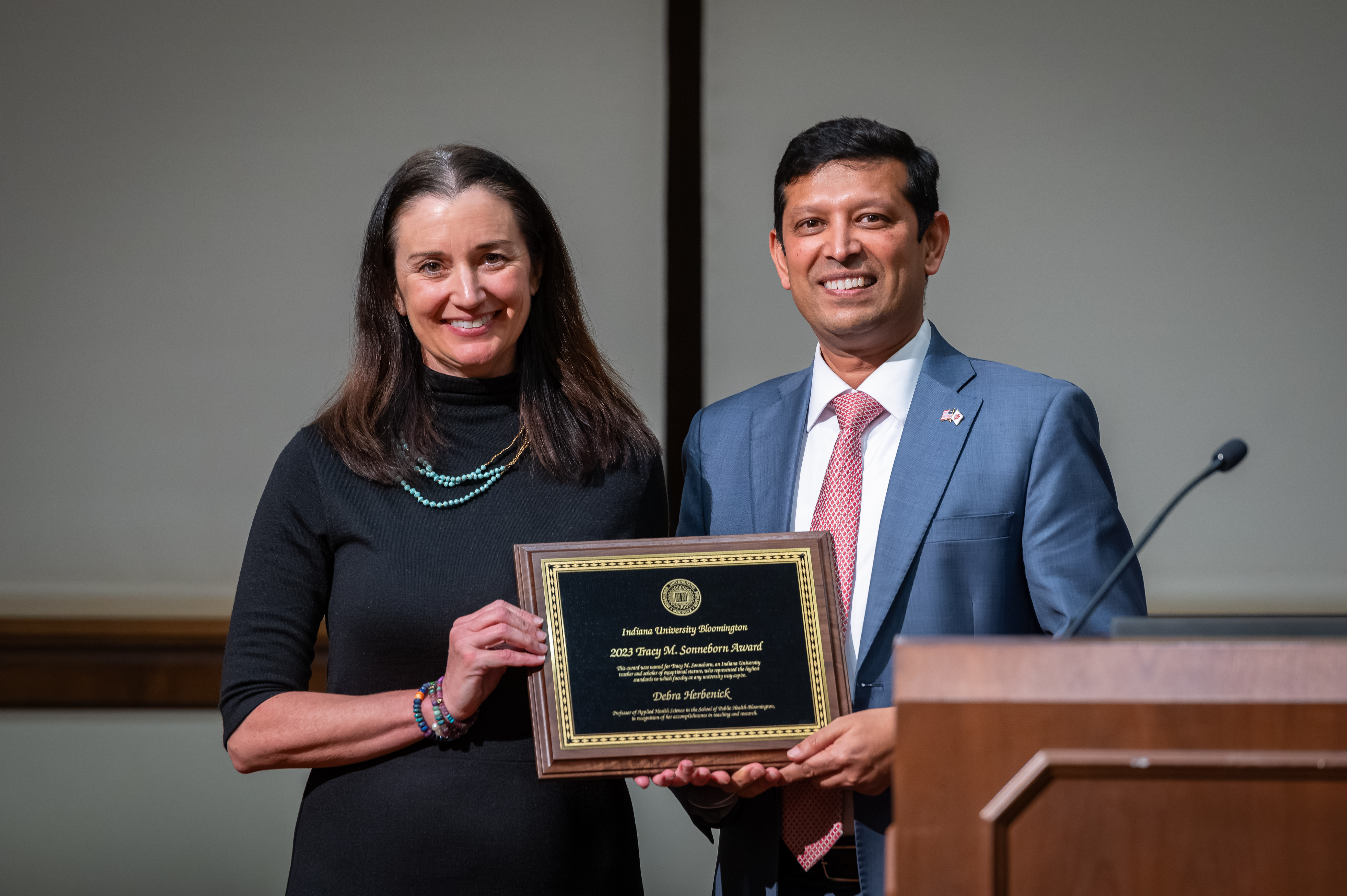 Debra Herbenick, the 2023 Sonneborn Award Winner, stands beside Provost Rahul Shrivastav, as he hands her a plaque with her name and the award title. 